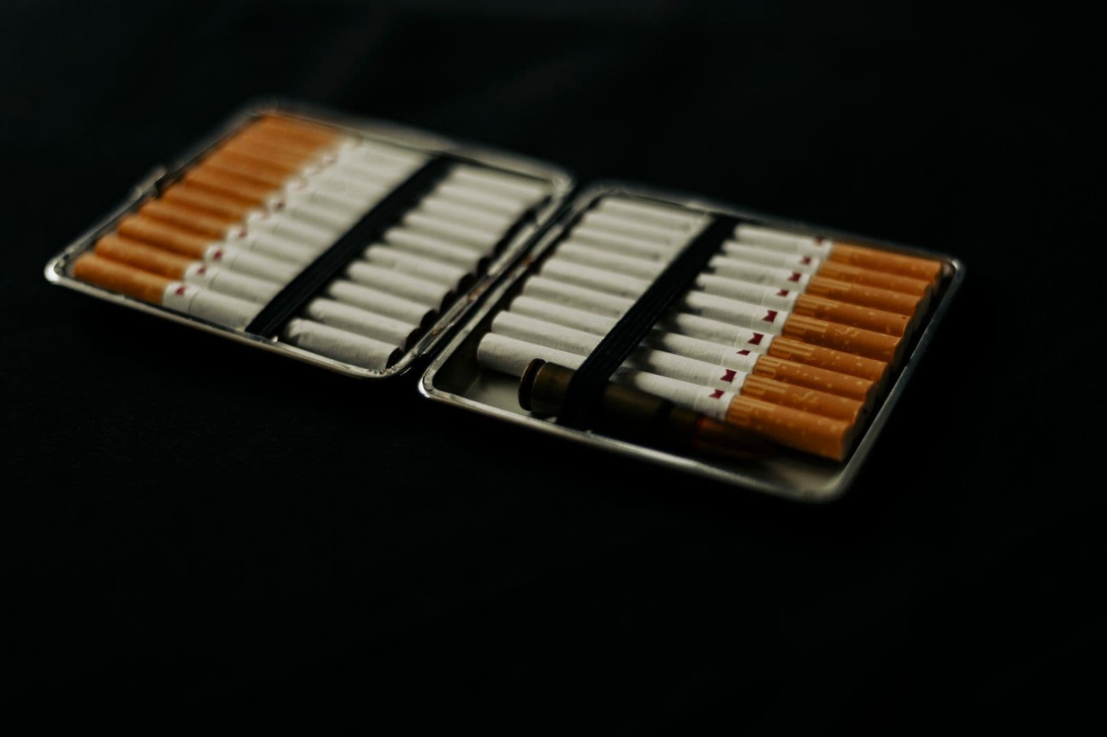 A metal cigarette case on a dark surface